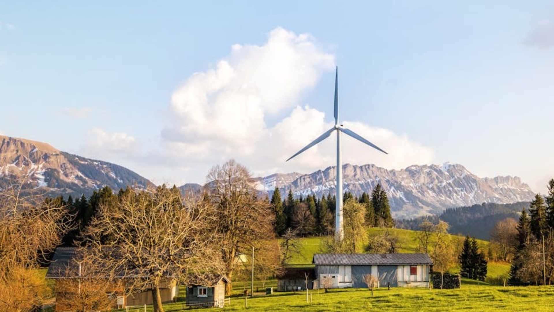 mountains scenery with trees, clouds, and wind turbines.