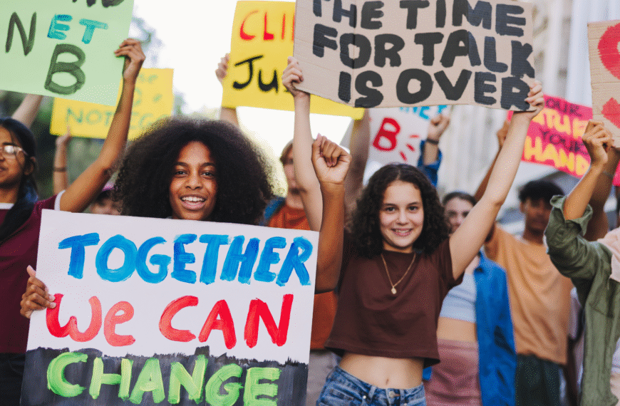 Youth protest against climate change. Group of multicultural youth activists carrying posters and banners while marching against global warming. Happy young people joining the global climate strike.