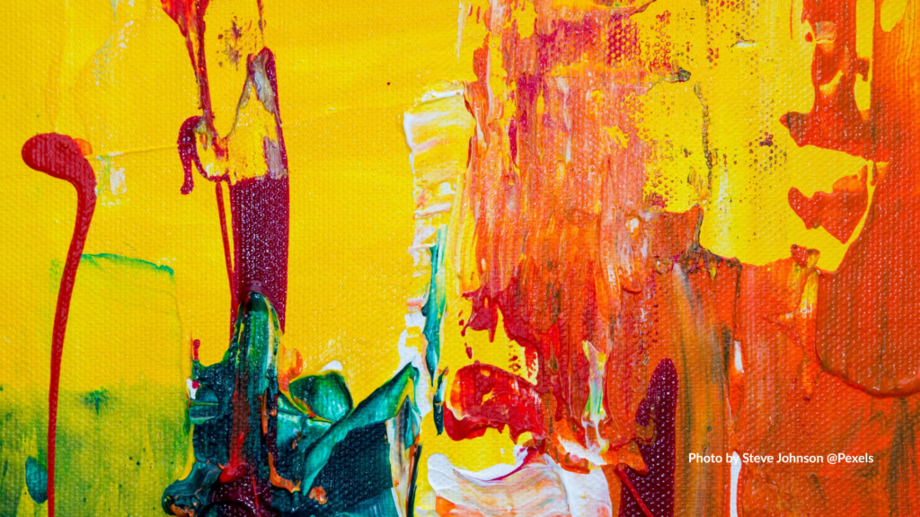 Abstract close-up of thick acrylic paint on canvas, featuring bold yellow, red, orange, green, and white brushstrokes layered with visible texture, drips, and palette-knife marks